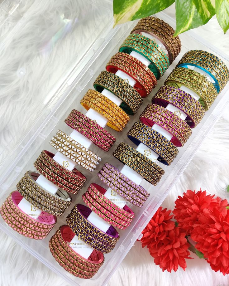 several different colored bracelets sitting in a plastic container on a white furnishing