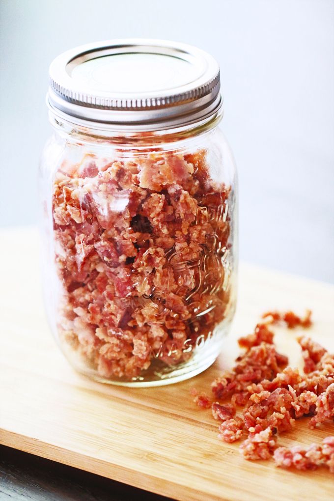 a jar filled with chopped meat sitting on top of a wooden cutting board