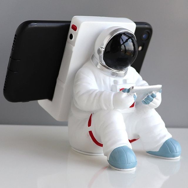 an astronaut figurine holding a cell phone