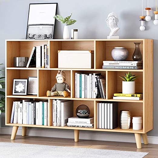 a bookshelf filled with lots of books next to a plant on top of a hard wood floor