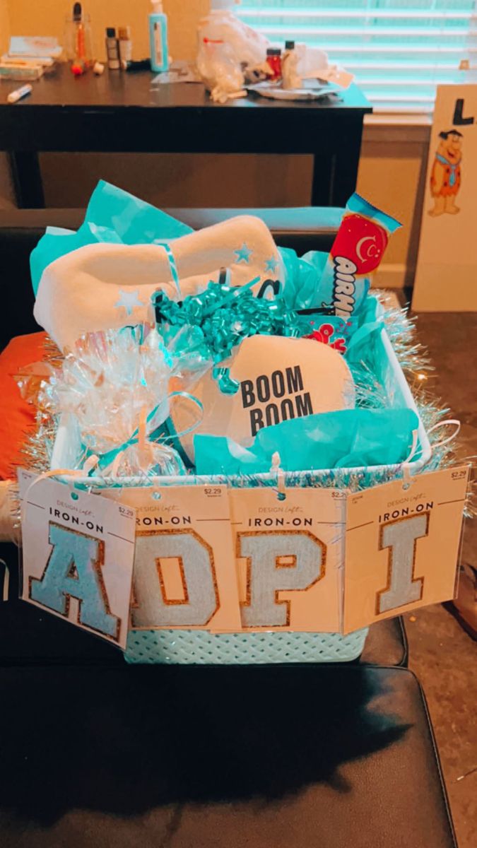 a gift box filled with blue and white items sitting on top of a couch in front of a window