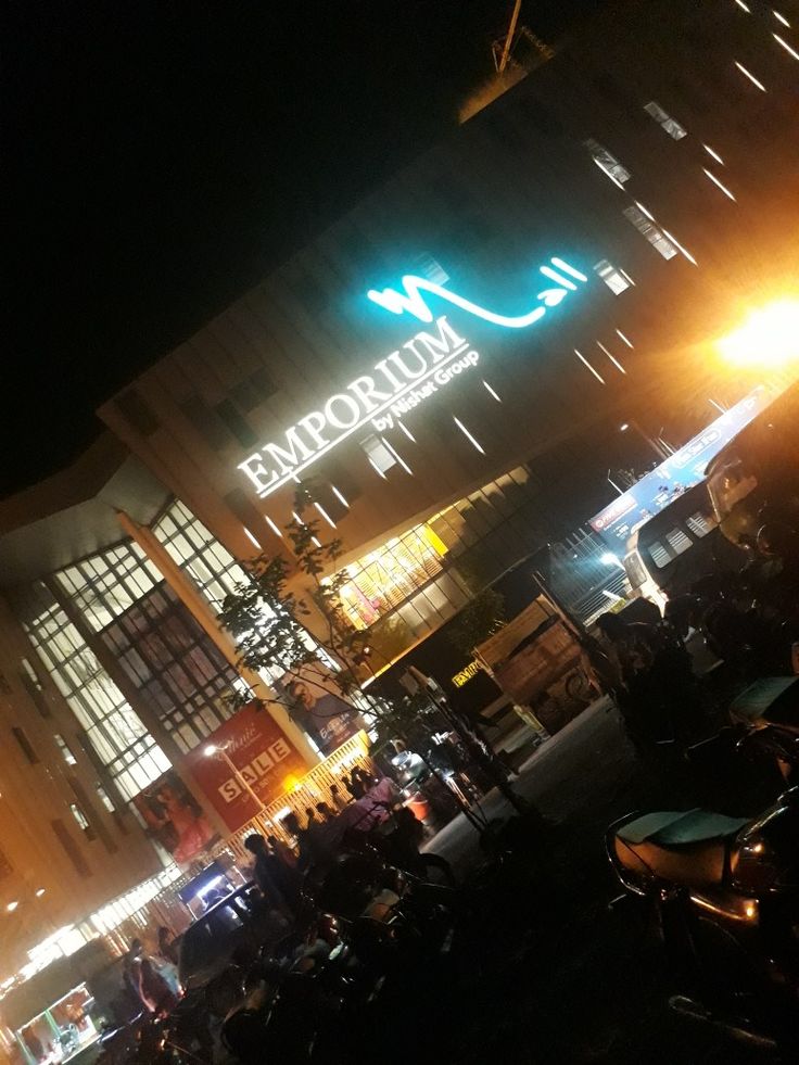 a group of motorcycles parked in front of a tall building at night with the name emporum on it