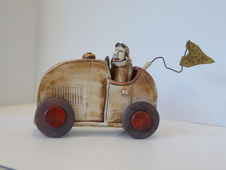 an old fashioned toy car with a man in the driver's seat and a kite flying above it