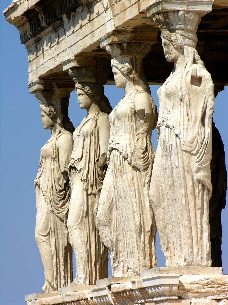 four statues are standing next to each other on the side of a building with a blue sky in the background