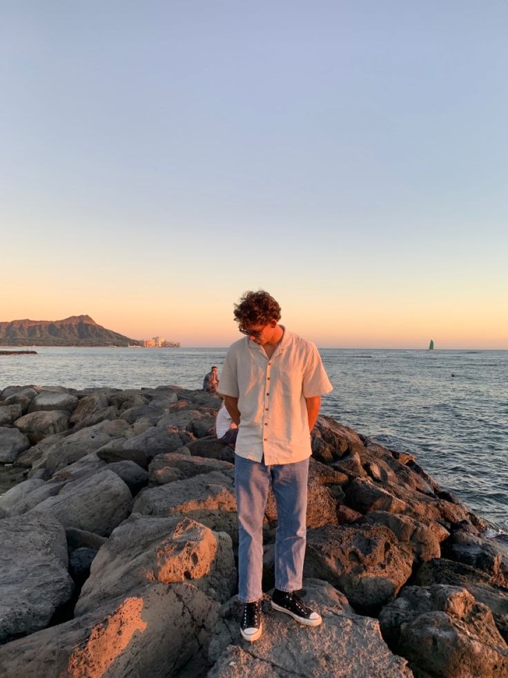 a man standing on rocks near the ocean