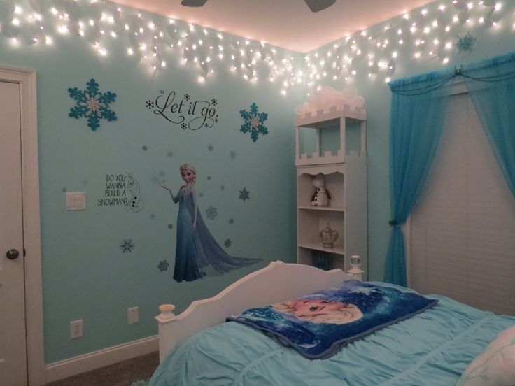 a bedroom decorated in blue and white with lights on the ceiling