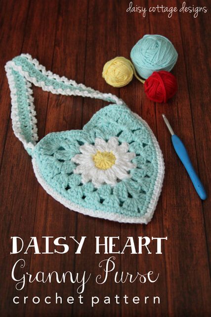 a crocheted purse with flowers and yarn next to it on a wooden table