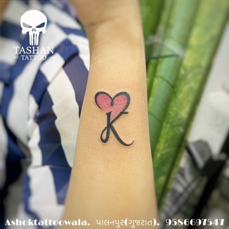 a woman with a tattoo on her arm holding a scissors and heart in the shape of a k