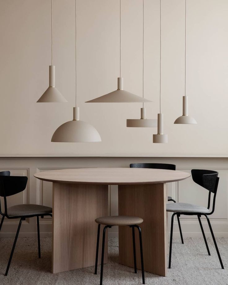 a dining room table with four chairs and three pendant lights hanging from the ceiling above it