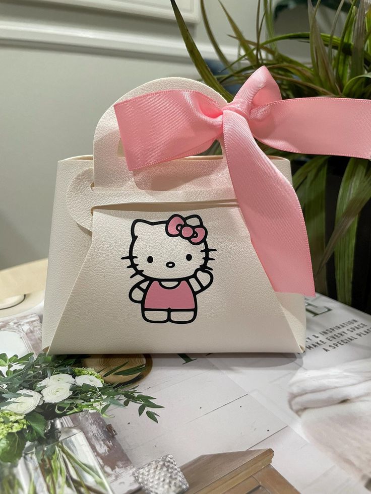 a hello kitty purse with a pink bow on it's handle sitting on a table