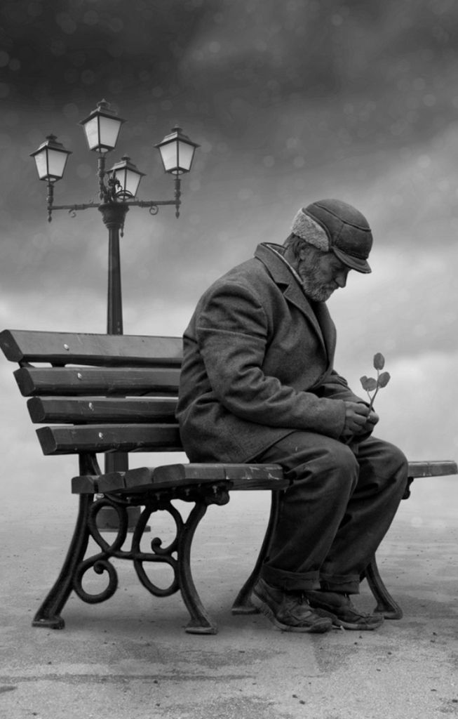 a man sitting on top of a bench next to a lamp post