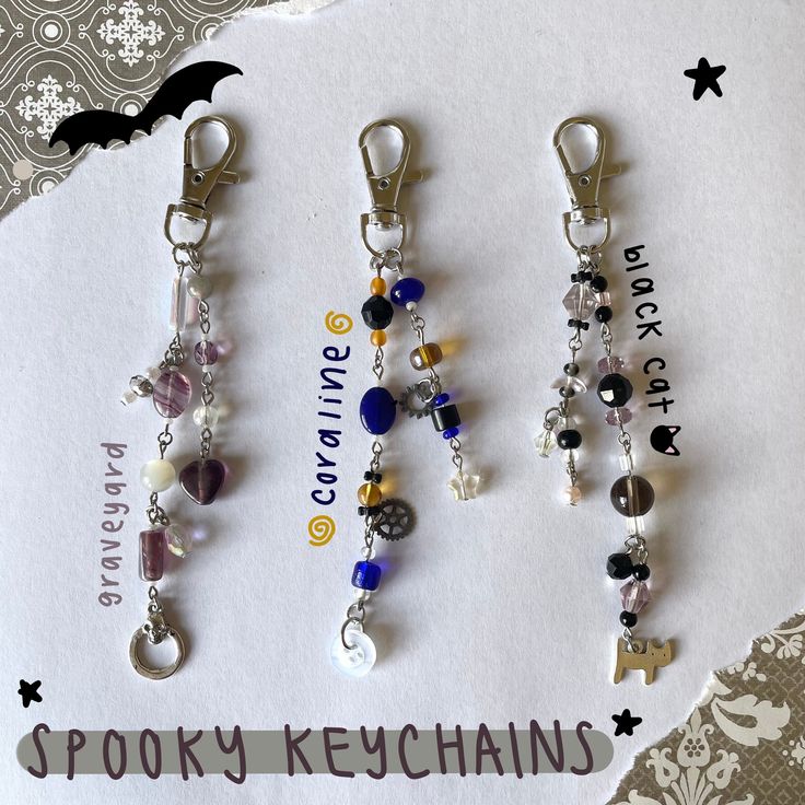 three keychains with charms attached to them sitting on top of a piece of paper