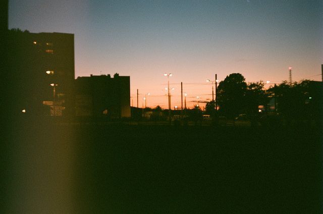 the sun is setting behind some buildings and power lines in the distance, as seen through a window