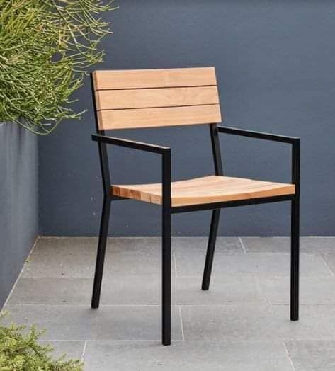 a wooden chair sitting on top of a cement floor next to a potted plant