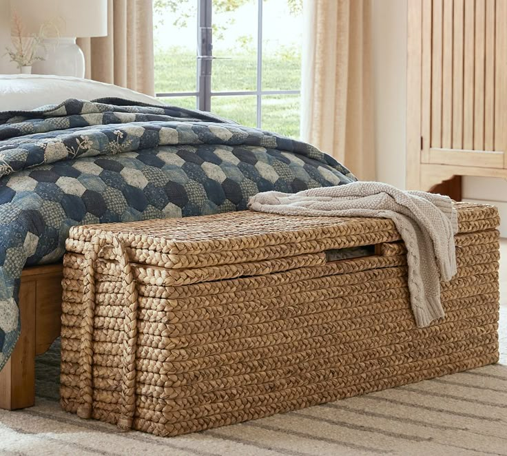 a bedroom with a bed, blanket and storage basket on the floor next to it