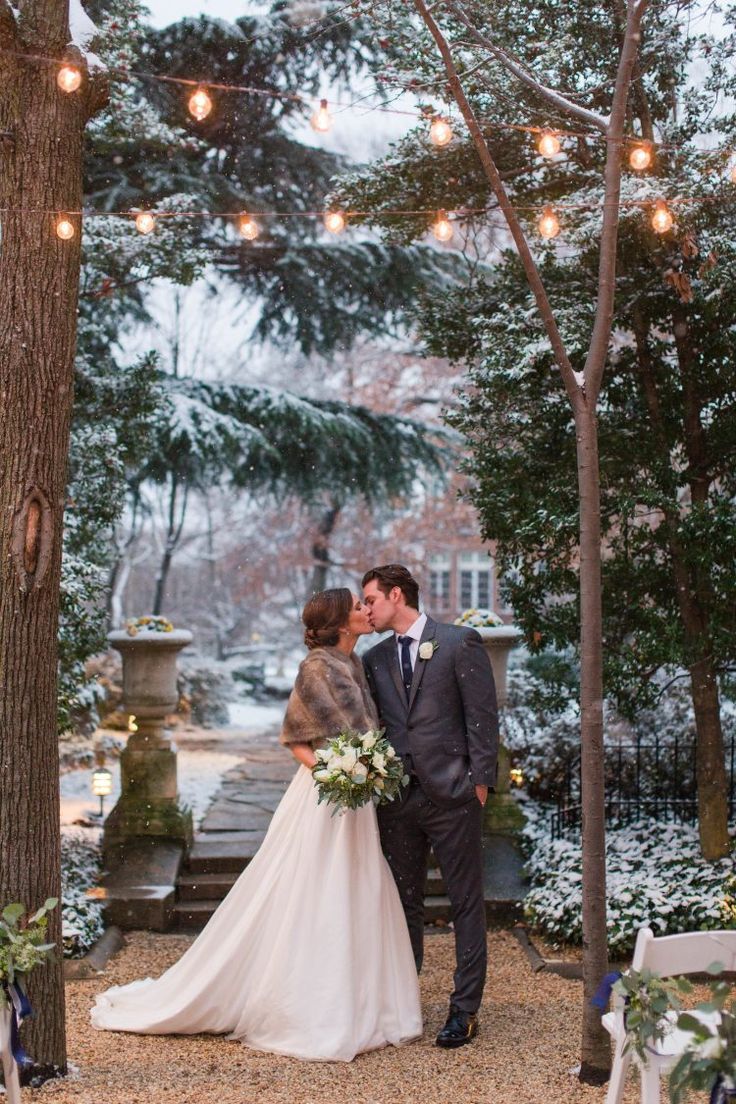 a bride and groom standing in front of a tree with lights strung from the branches