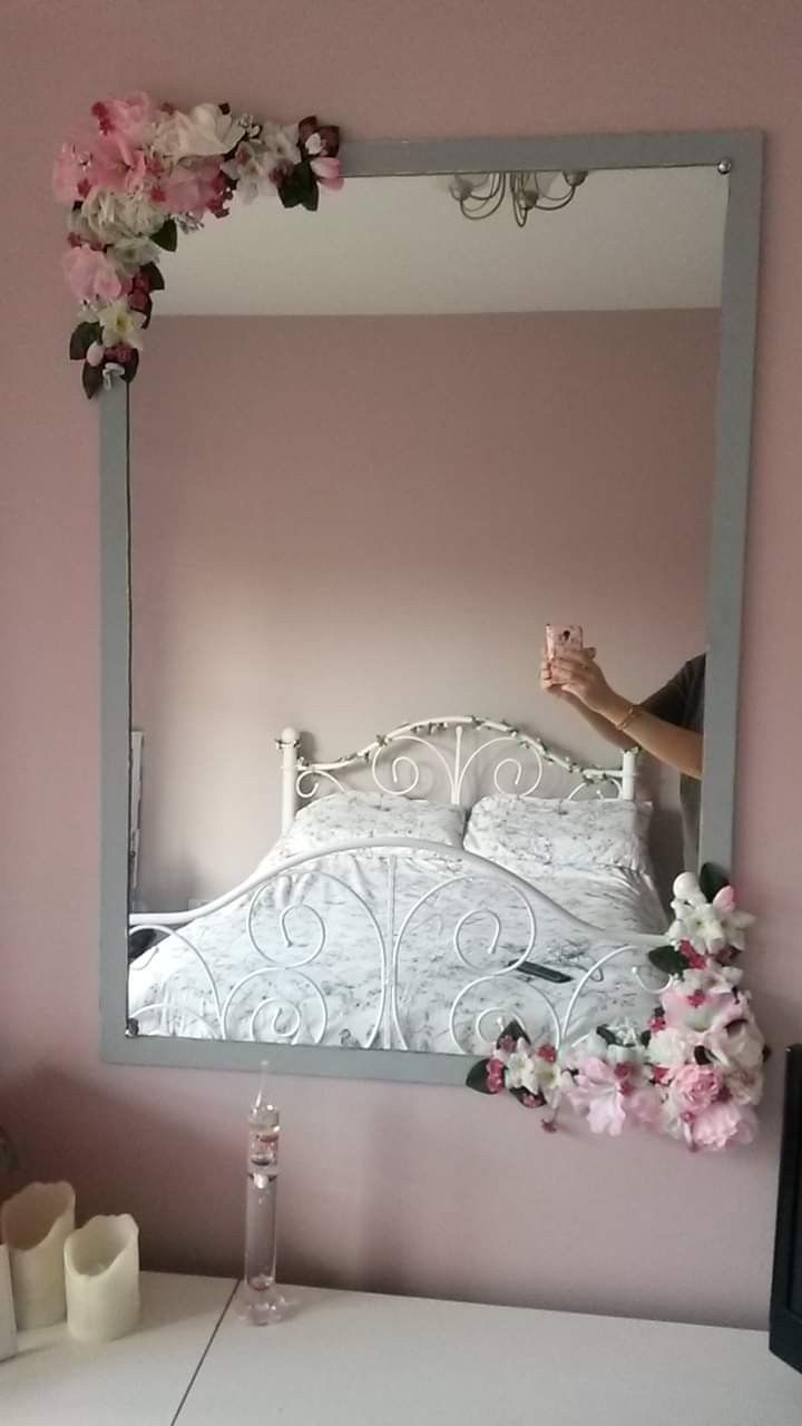 a person taking a photo of a bed in a mirror with flowers on the wall