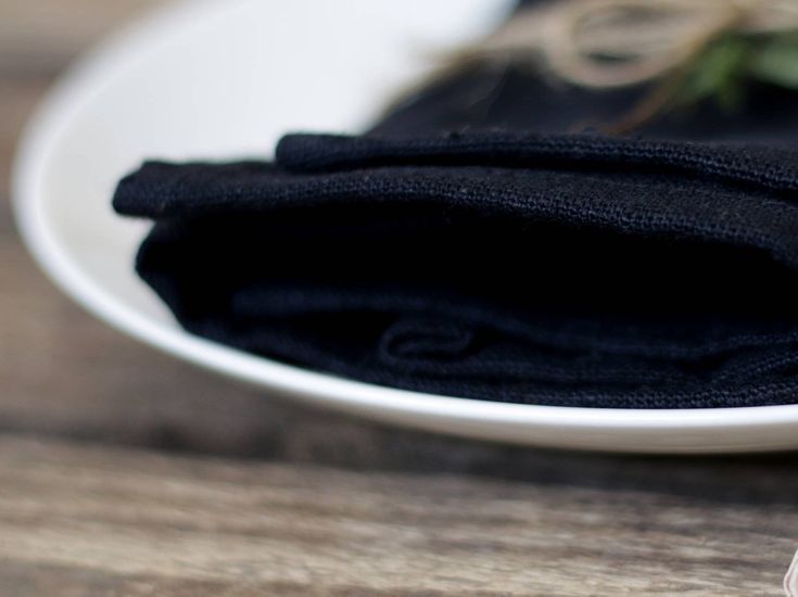 a white plate topped with black napkins on top of a wooden table