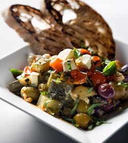 a white plate topped with a salad next to a piece of bread