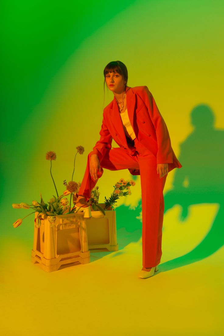 a man in a red suit is leaning on a planter with flowers inside it