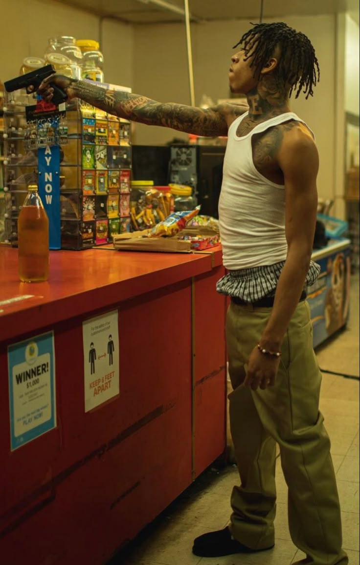 a man with dreadlocks standing in front of a counter