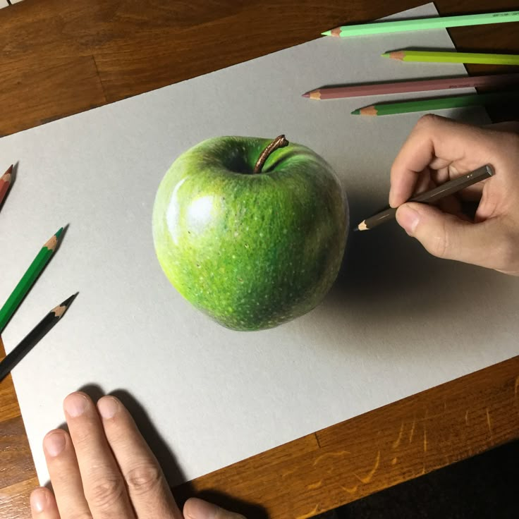 someone is drawing an apple with colored pencils