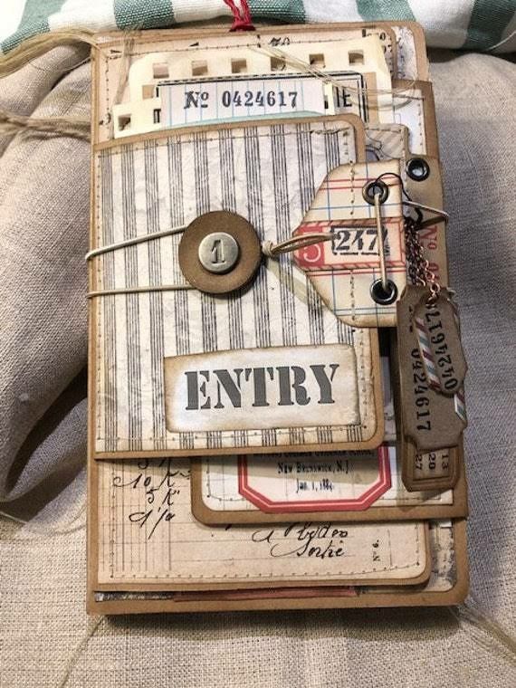 an altered book with buttons and tags attached to the cover is sitting on a couch