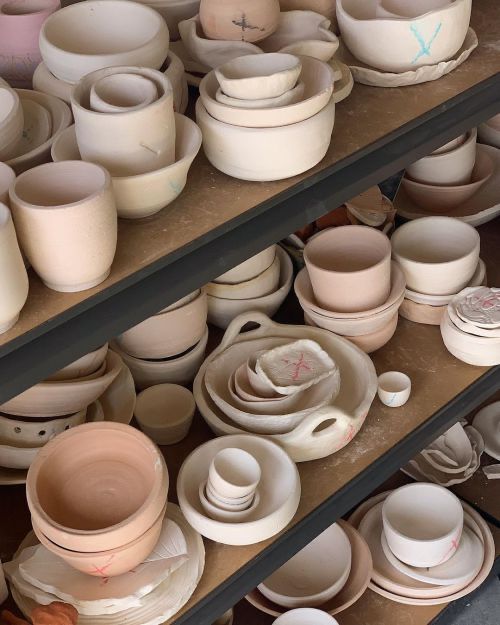 many bowls and plates are stacked on shelves