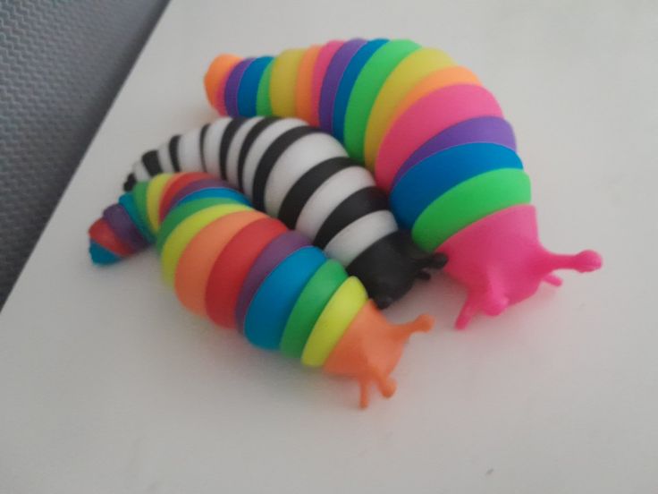 three colorful toy caterpillars sitting on top of a white table next to each other