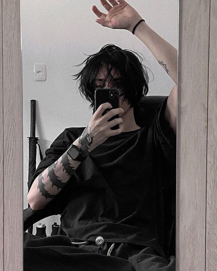 a man with tattoos on his arm taking a selfie in front of a mirror