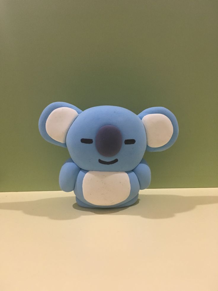 a small blue koala toy sitting on top of a table next to a green wall