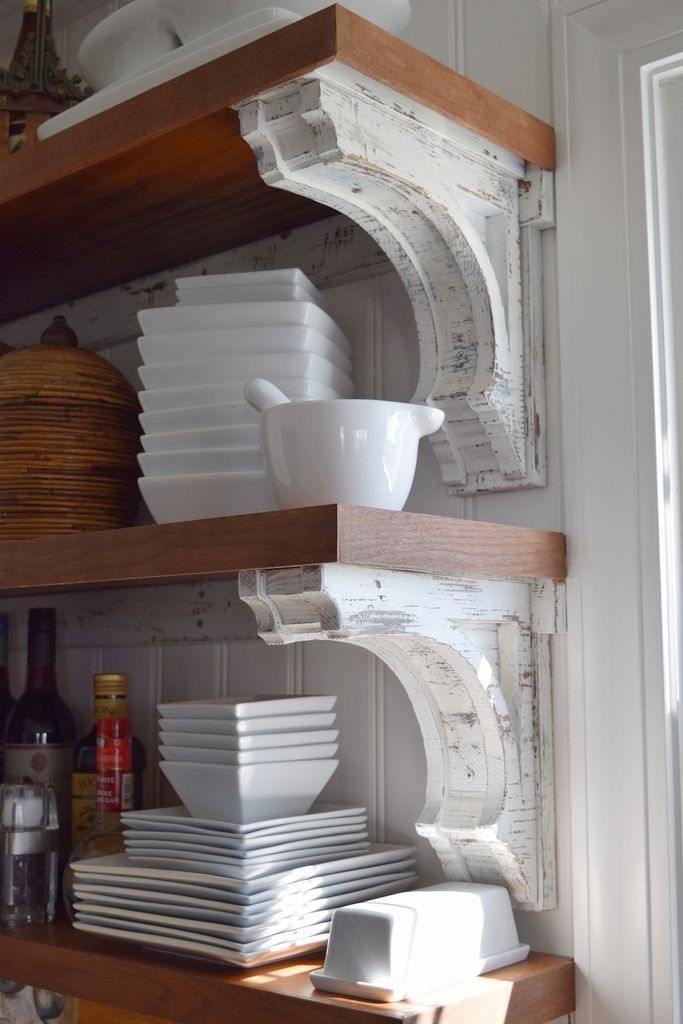 white dishes are stacked on wooden shelves in the kitchen