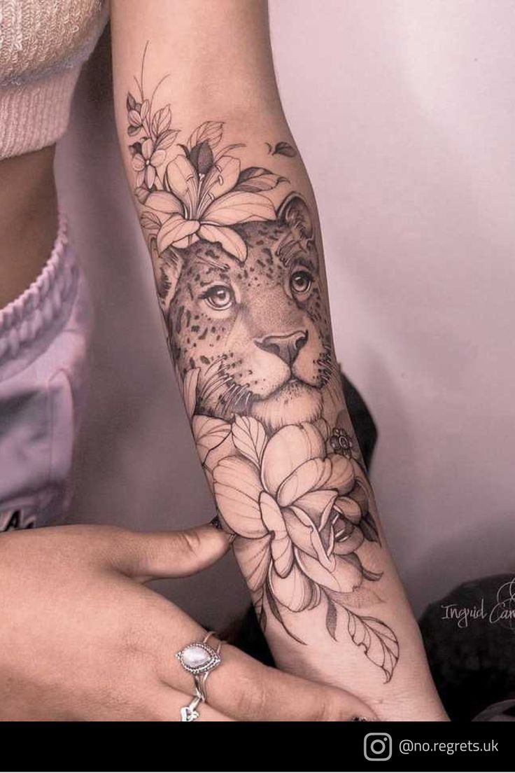 a woman's arm with flowers and a cheetah tattoo on the arm