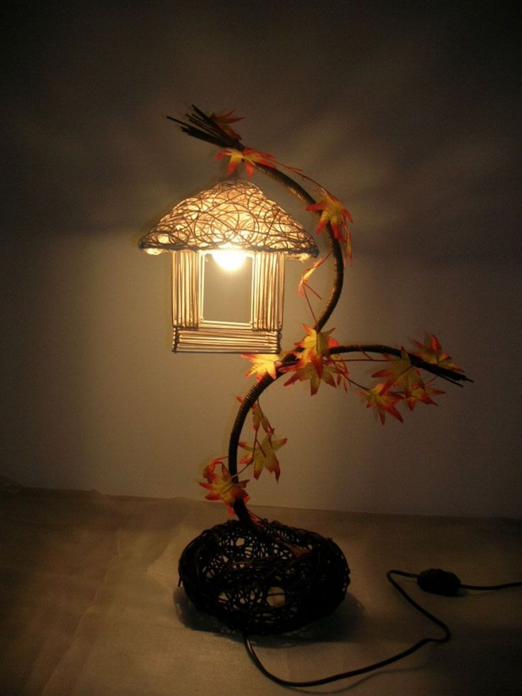 a lamp that is sitting on top of a table next to a black object with leaves growing out of it