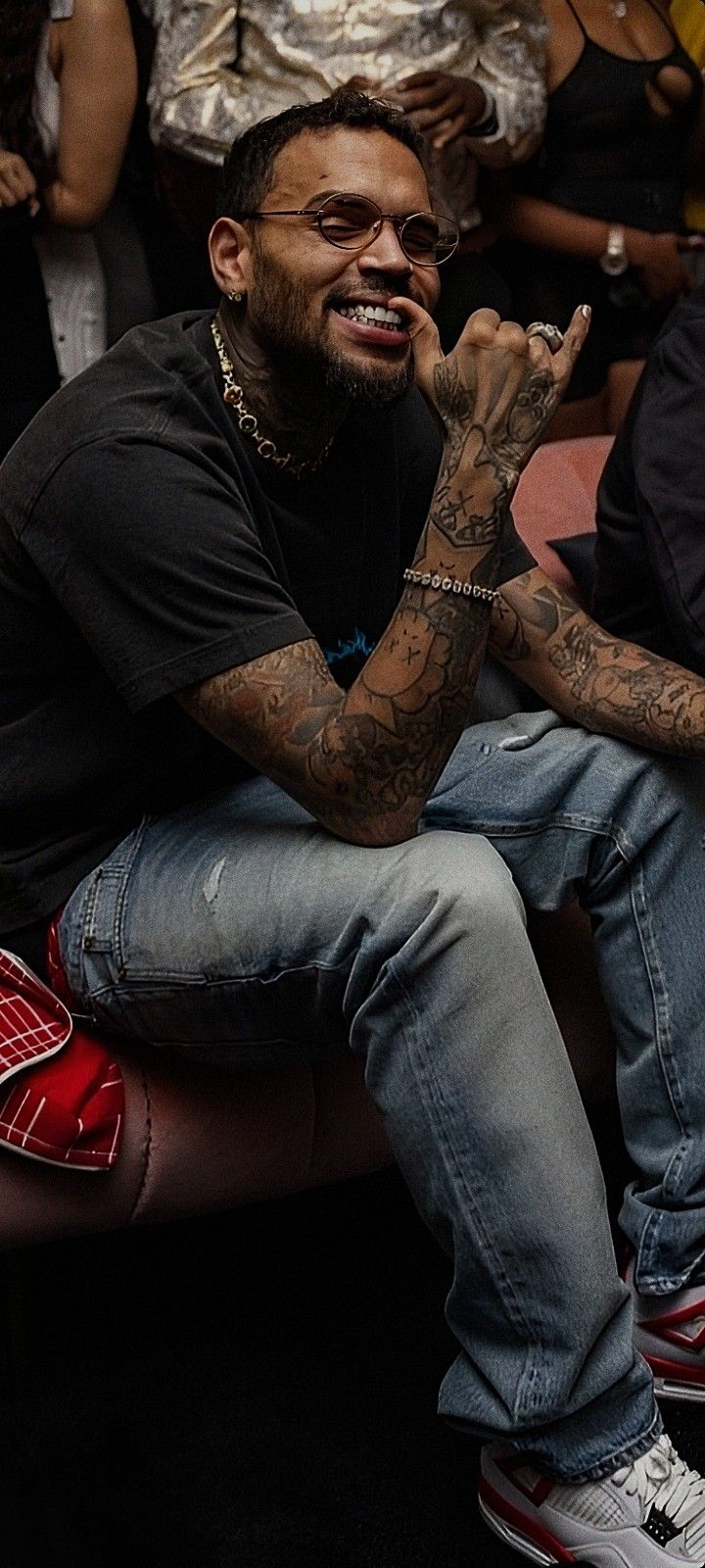 a man with tattoos sitting in front of a crowd