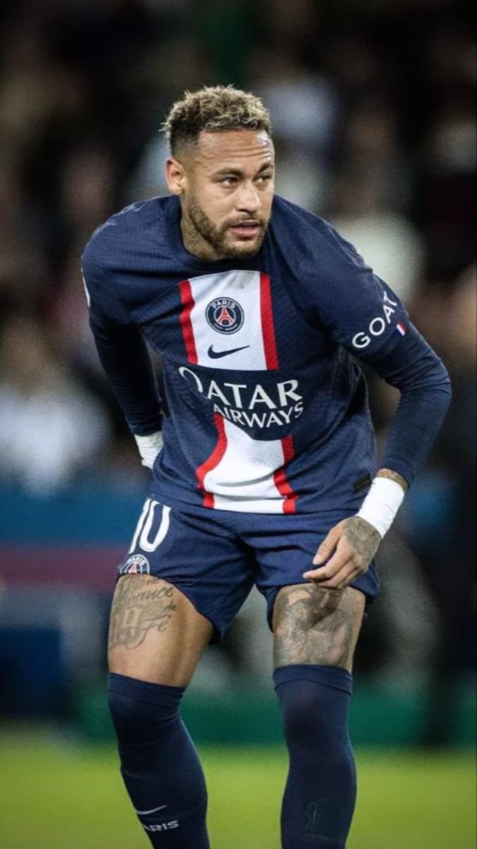 a soccer player is standing on the field with his hands in his pockets and looking down