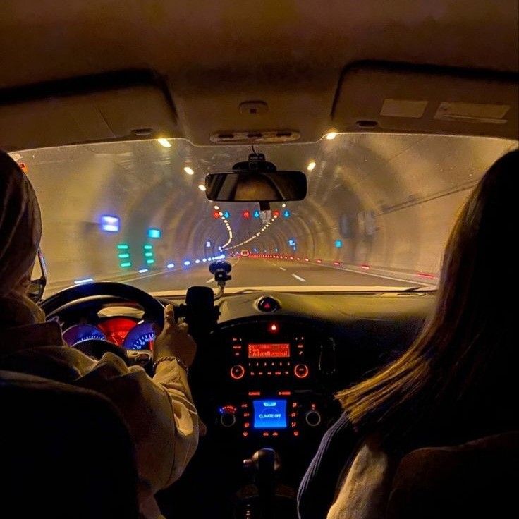 two people in a car driving through a tunnel with lights on the side and inside