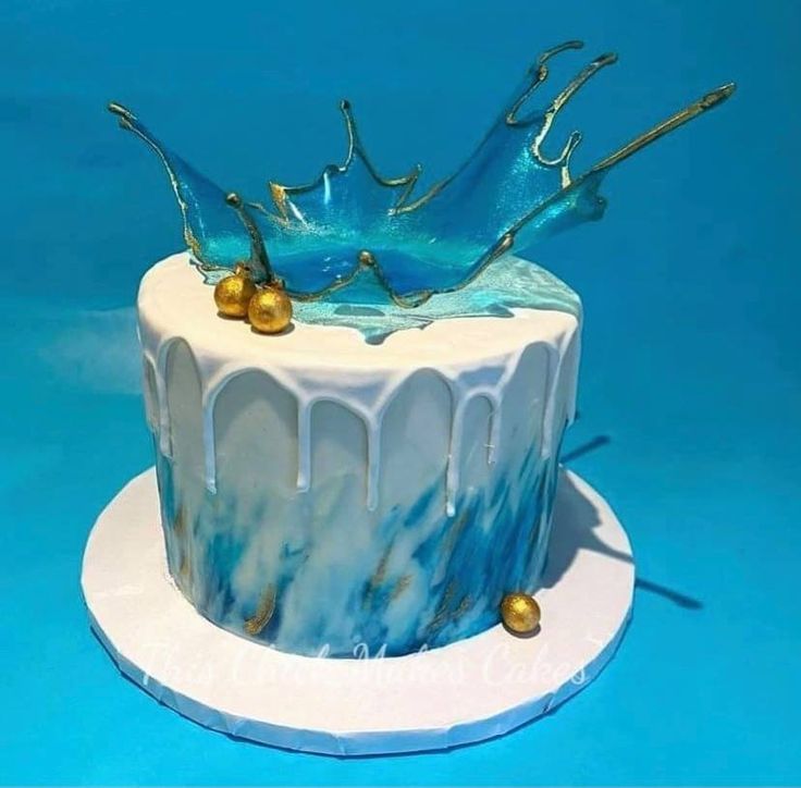 there is a blue and white cake with gold decorations on the top, sitting on a plate