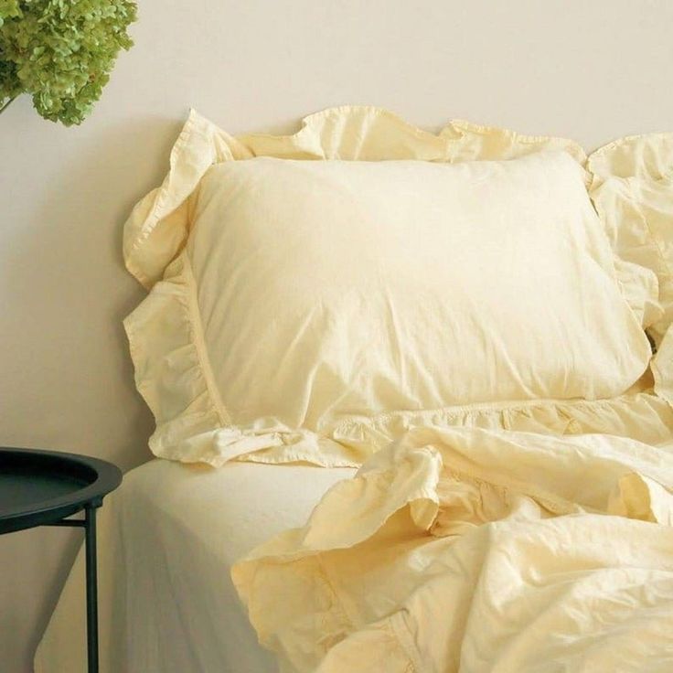 a bed with white sheets and pillows next to a small black table on the floor