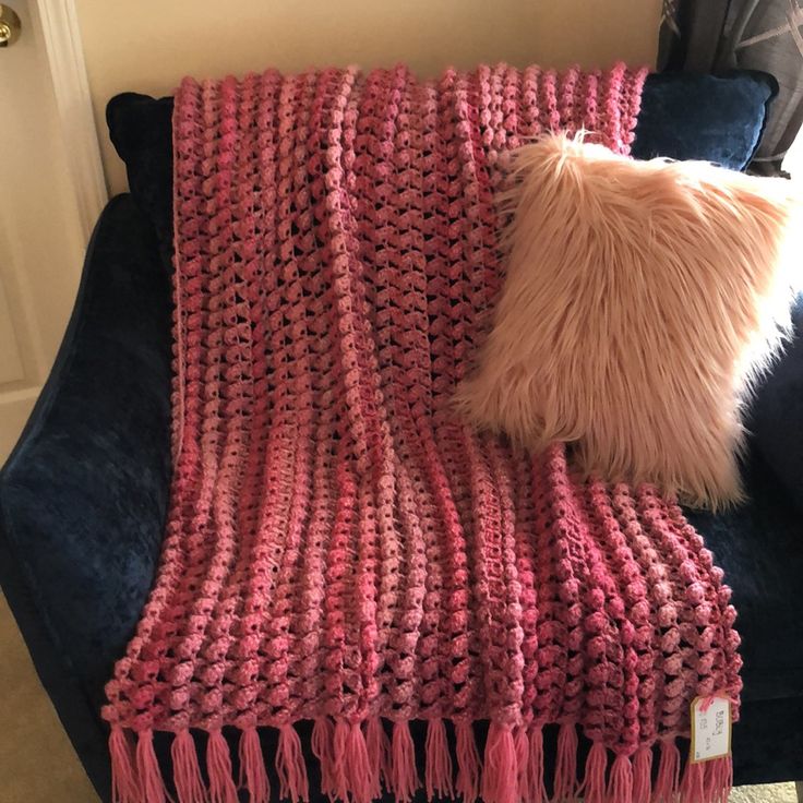 a pink blanket sitting on top of a blue couch