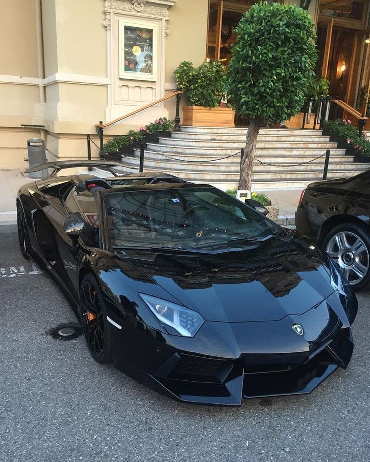 two black sports cars parked in front of a building with steps leading up to it