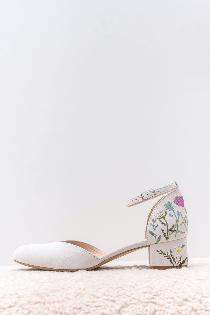 a pair of white shoes with flowers painted on them