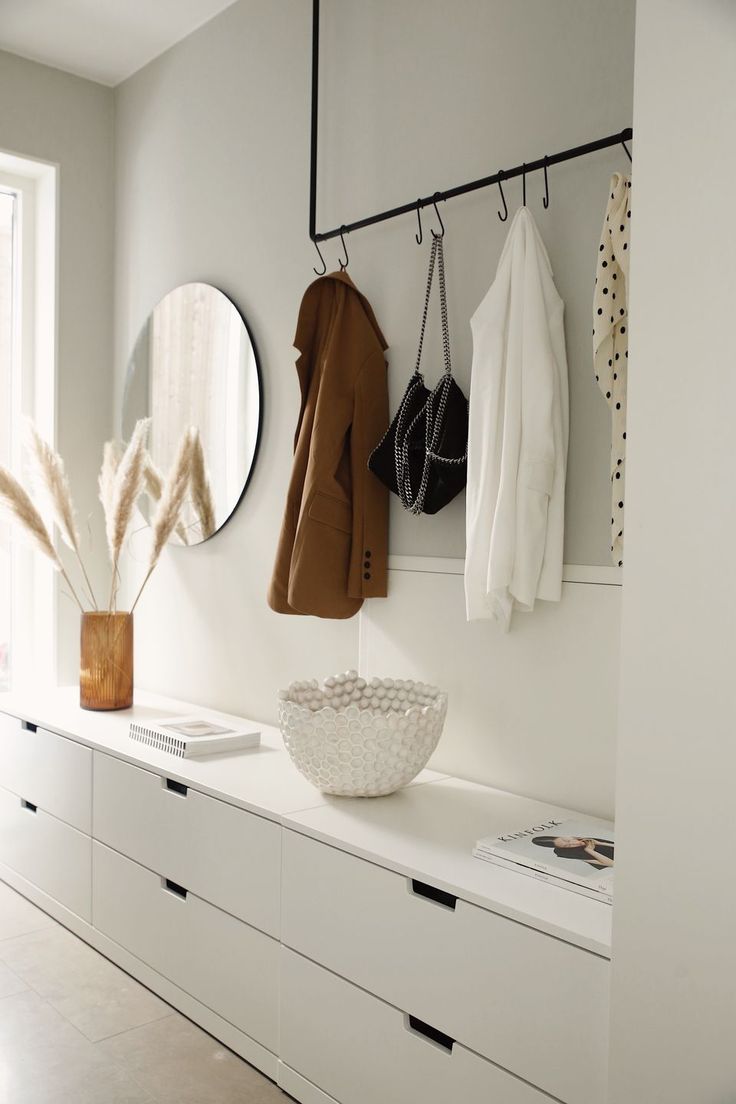 a room with white furniture and mirrors on the wall, including a coat hanger