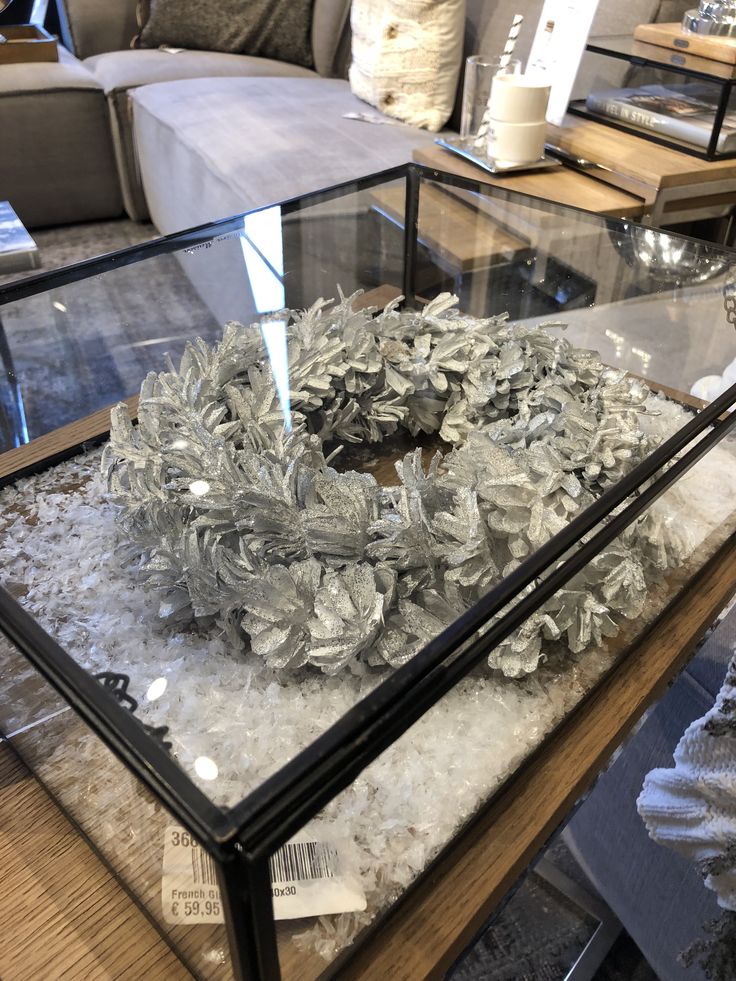 a glass table with a wreath on it in front of a couch and coffee table