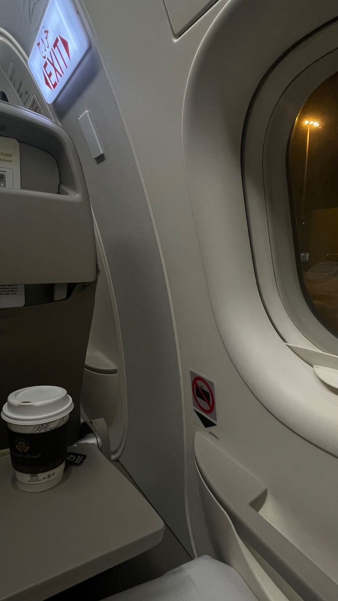 an empty airplane seat with a cup of coffee on the table in front of it