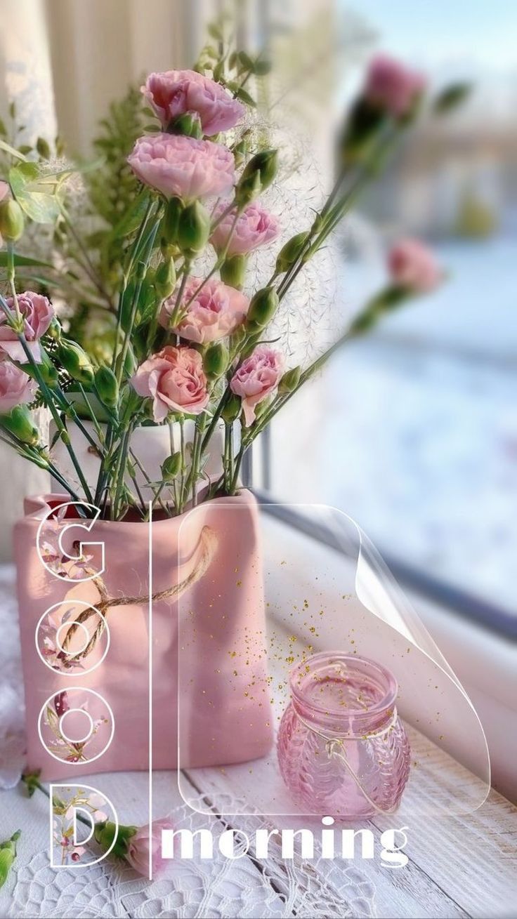 a pink vase with flowers in it sitting on a window sill next to a pair of wedding rings