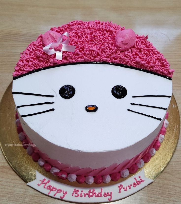 a birthday cake decorated with pink frosting and a cat's face