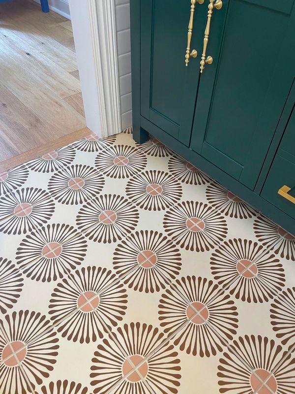 a kitchen floor with an intricate design on it's side and green cabinetry in the background