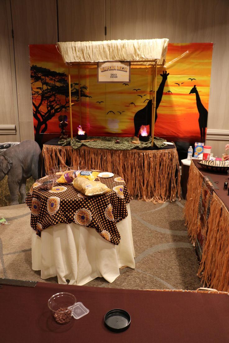 the table is set up for an african themed party with giraffes in the background