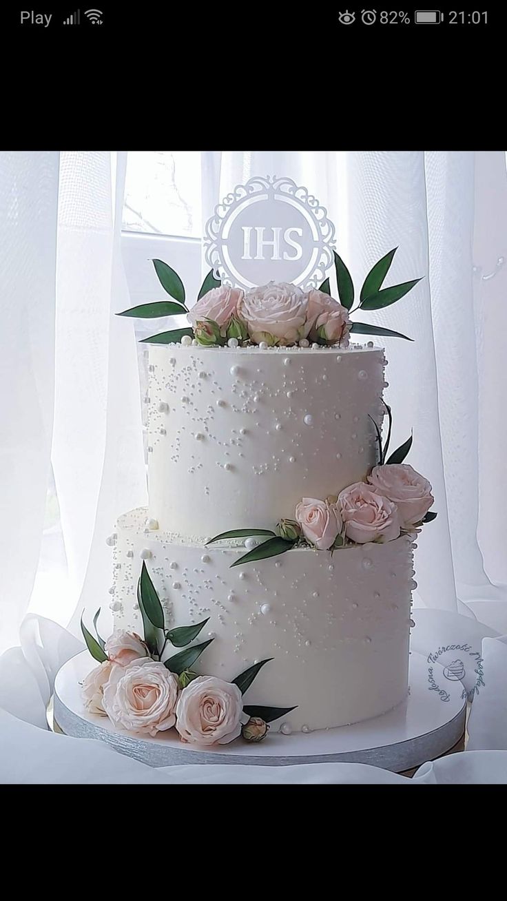 a three tiered wedding cake with pink flowers on the top and green leaves on the bottom